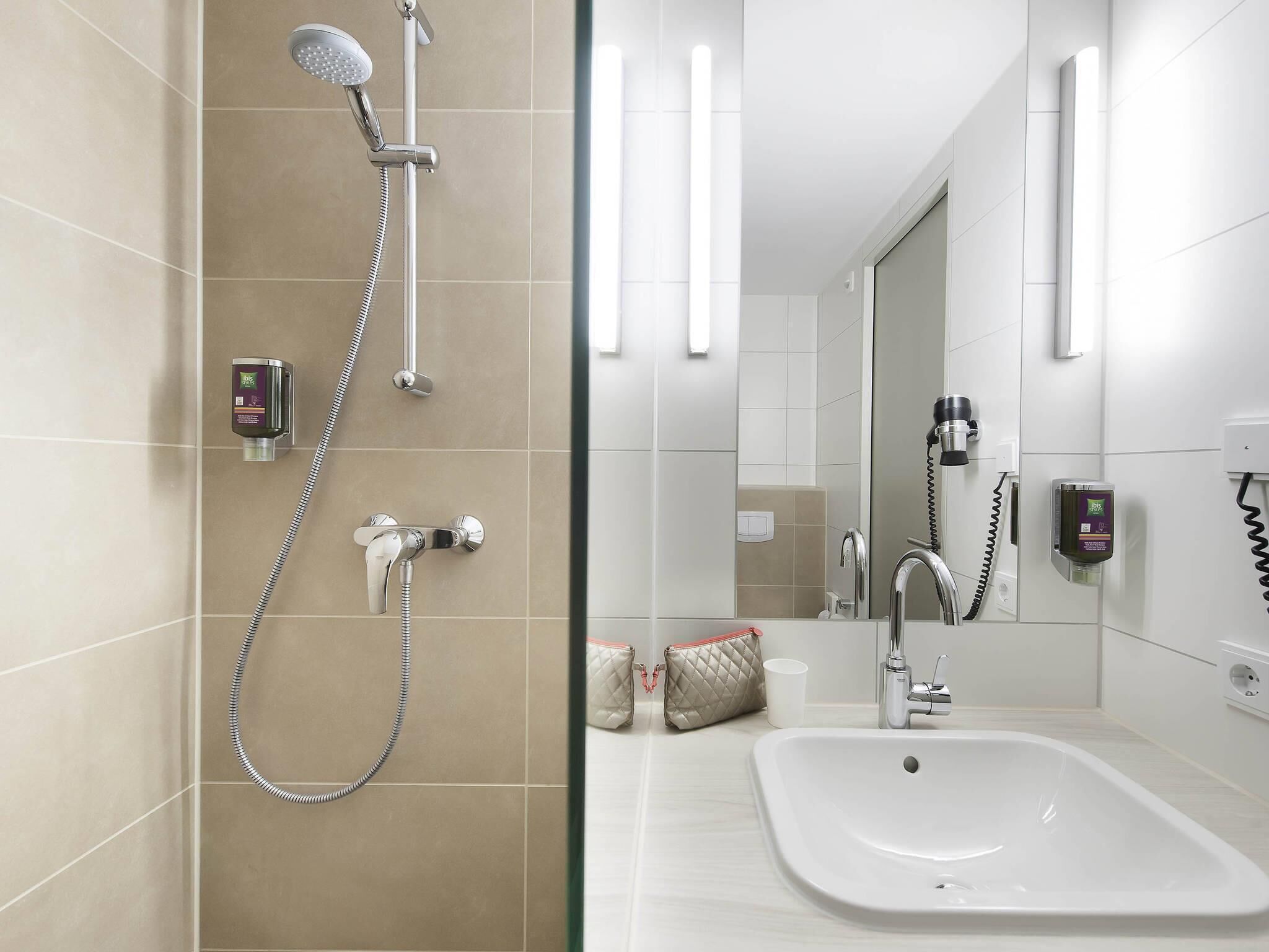 Un baño moderno con ducha, lavamanos y espejo.