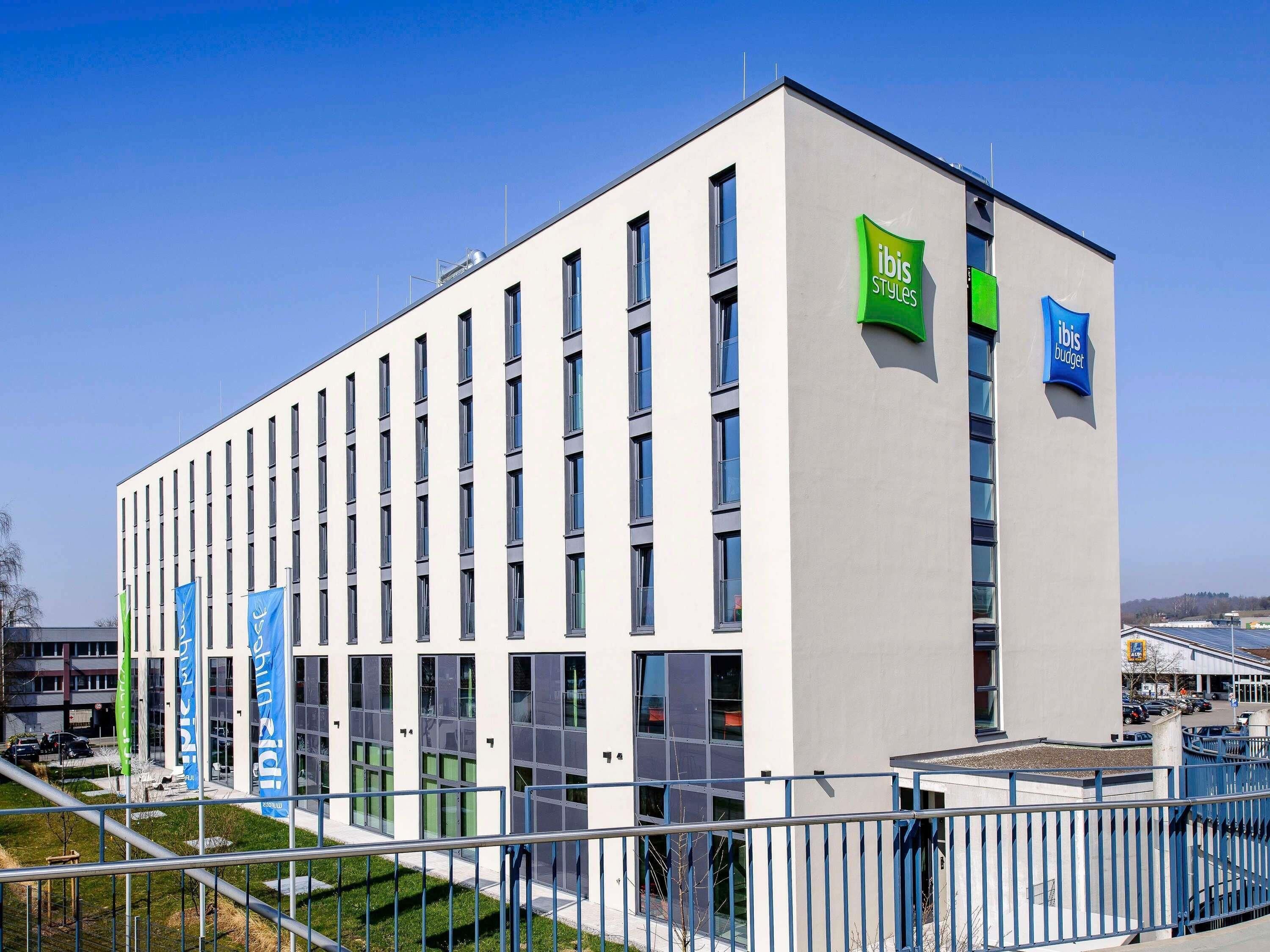 A modern building with a flat roof, multiple windows, and flags.