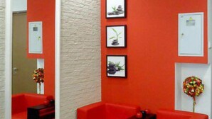 Une pièce avec des canapés rouges, une table noire et des tableaux encadrés accrochés au mur.