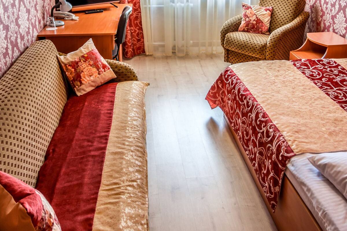 Una habitación de hotel con una cama, un sofá, un escritorio con una computadora y una silla.