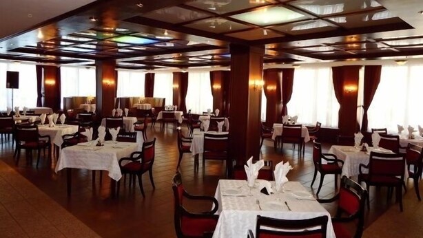 Un vaste espace dédié à la salle à manger, avec de nombreuses tables et chaises, de grandes fenêtres et un plafond haut agrémenté de lucarnes.