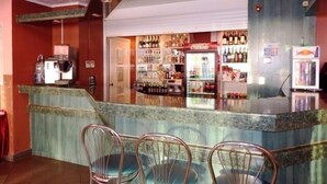 Un espace bar comprenant un comptoir, des sièges et un réfrigérateur.