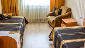 Une chambre d’hôtel avec deux lits, une télévision, une chaise et une petite table.