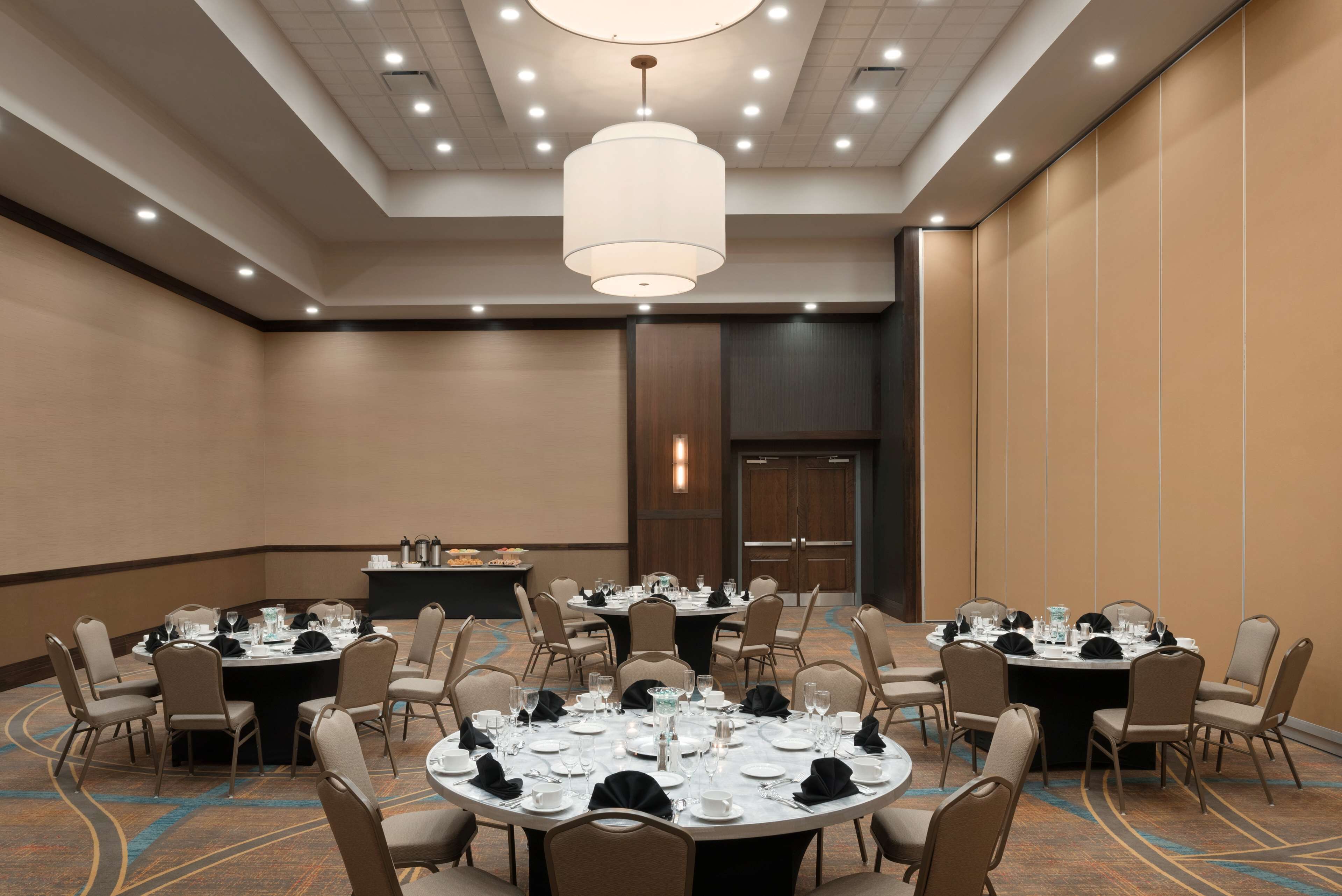 Une salle de conférence équipée de tables rondes, de chaises et d’un luminaire central.