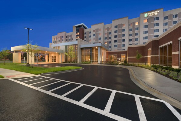 A modern hotel with a prominent "Embassy Suites" sign, a spacious entrance, and a well-maintained driveway.