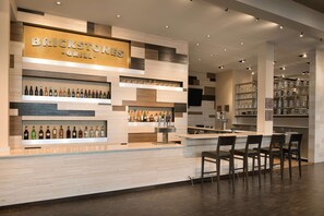 Un bar restaurante de ladrillo con detalles de madera y metal, estantes con botellas y una barra con sillas.