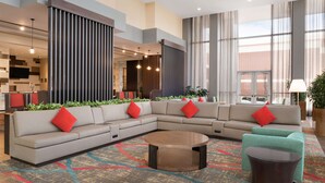 A modern hotel lobby with a large sectional sofa, a round coffee table, and a patterned carpet. - Embassy Suites by Hilton Chicago Naperville (Naperville)