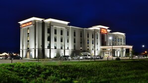 Un hôtel moderne doté d’un toit plat et d’une enseigne indiquant « Hampton Inn & Suites ».