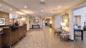 Un hall d’hôtel comprenant un comptoir d’accueil, un espace salon et un tapis à motifs.