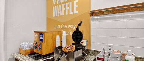 Angolo dedicato ai waffle, con una macchina per waffle, condimenti e un cartello per The Hampton Waffle.