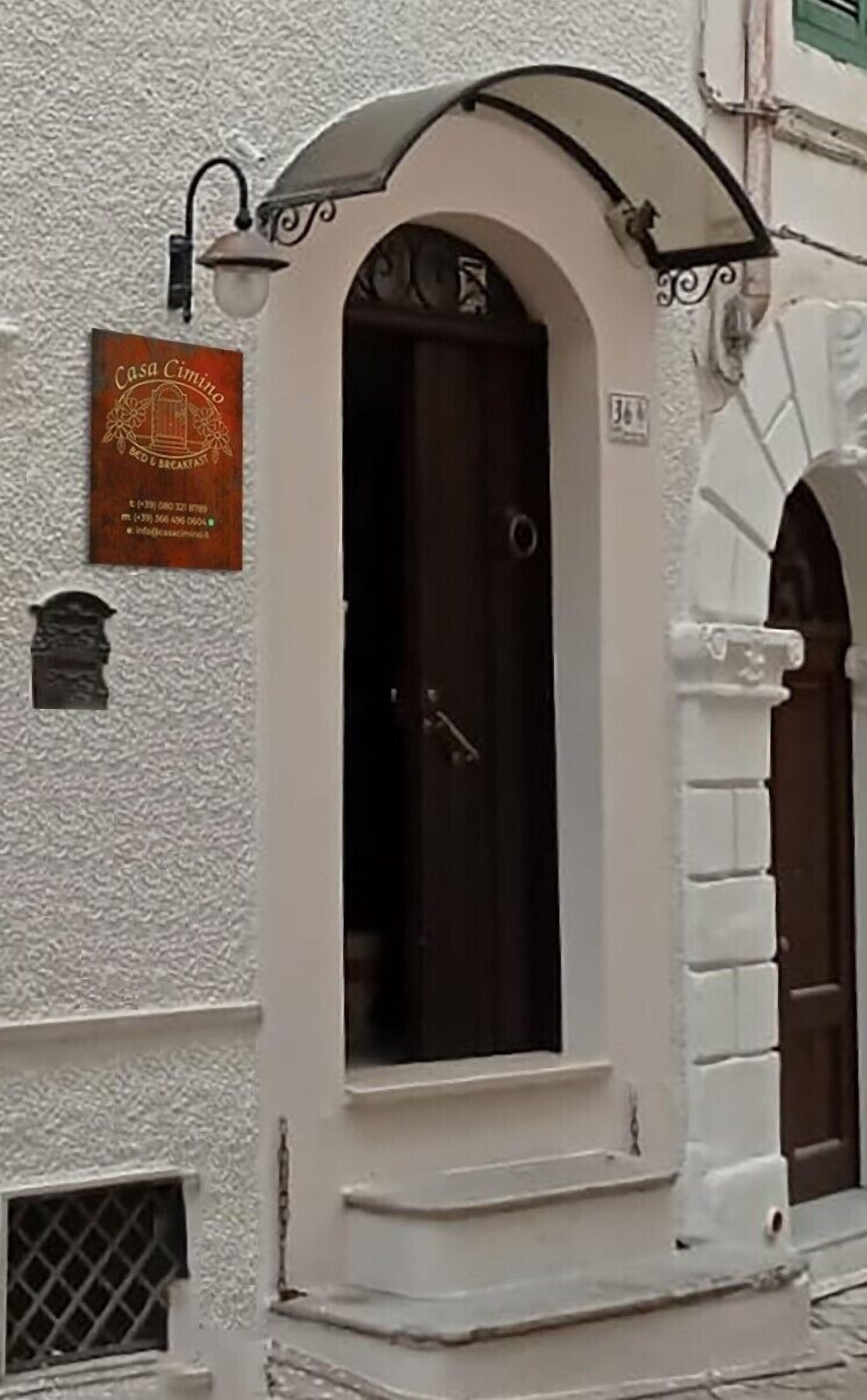 Un bâtiment avec une enseigne indiquant « Casa Cimino, chambre d’hôtes », et une porte en bois sombre.