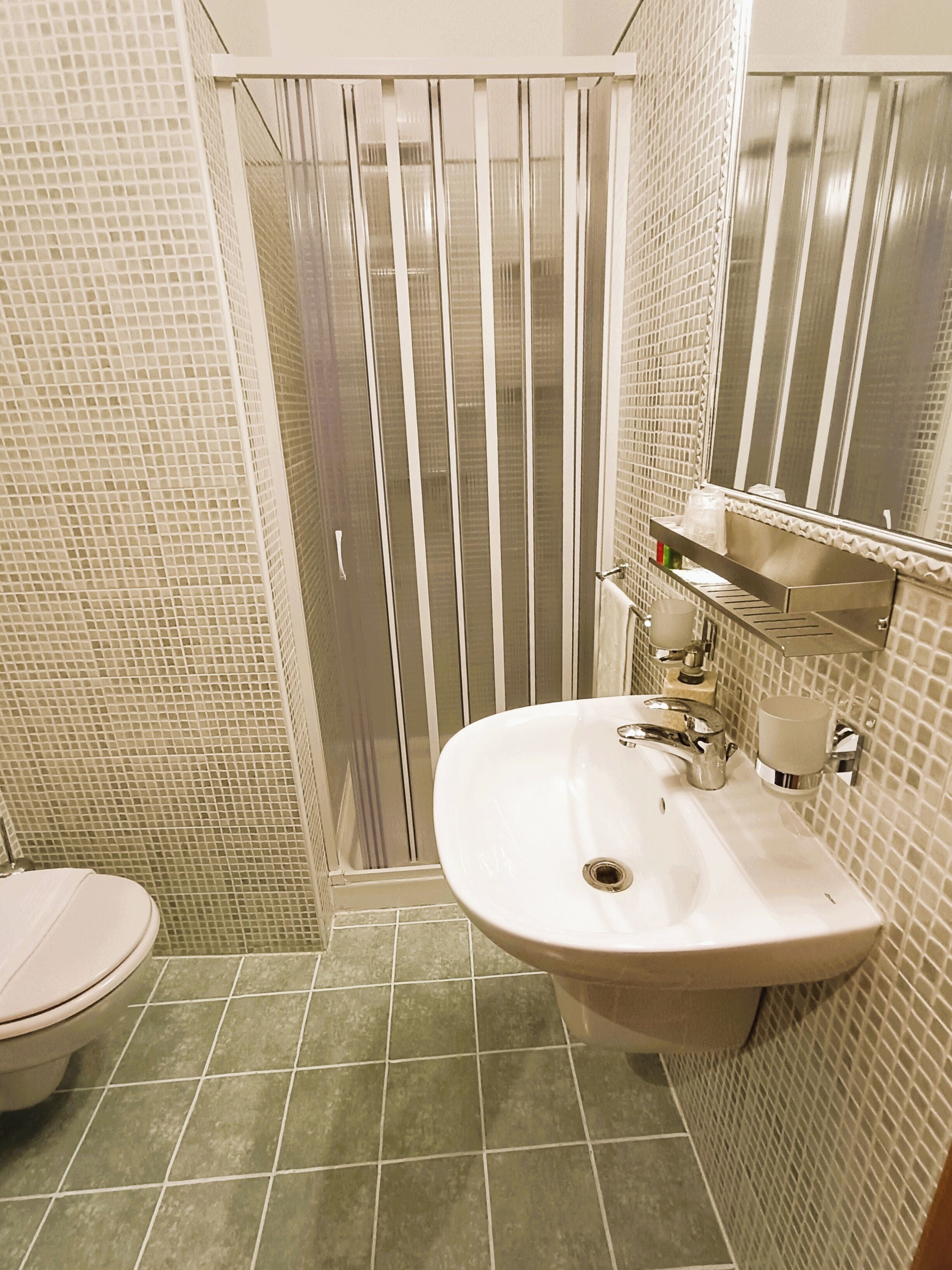 Un bagno con il water, un lavandino e una cabina doccia.