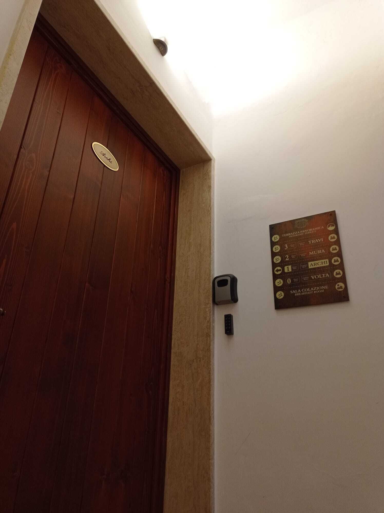 A wooden door with a nameplate and a wall-mounted sign indicating room numbers and names.