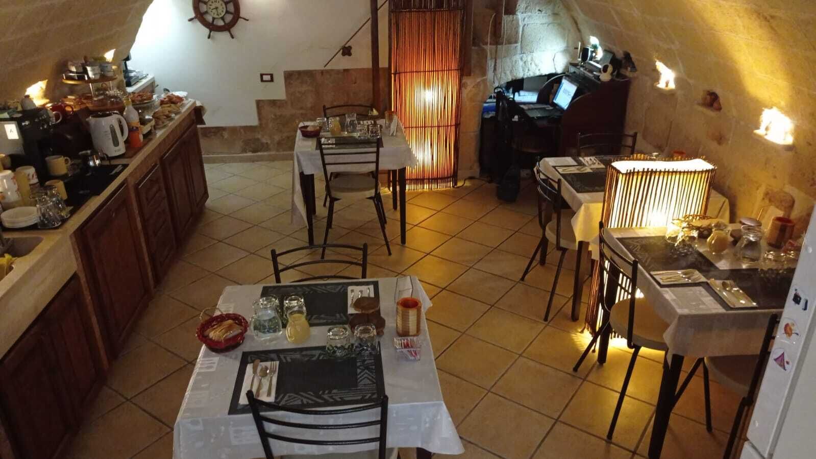A cozy kitchen with a dining area, featuring a stone wall, wooden cabinets, and a rustic ambiance.