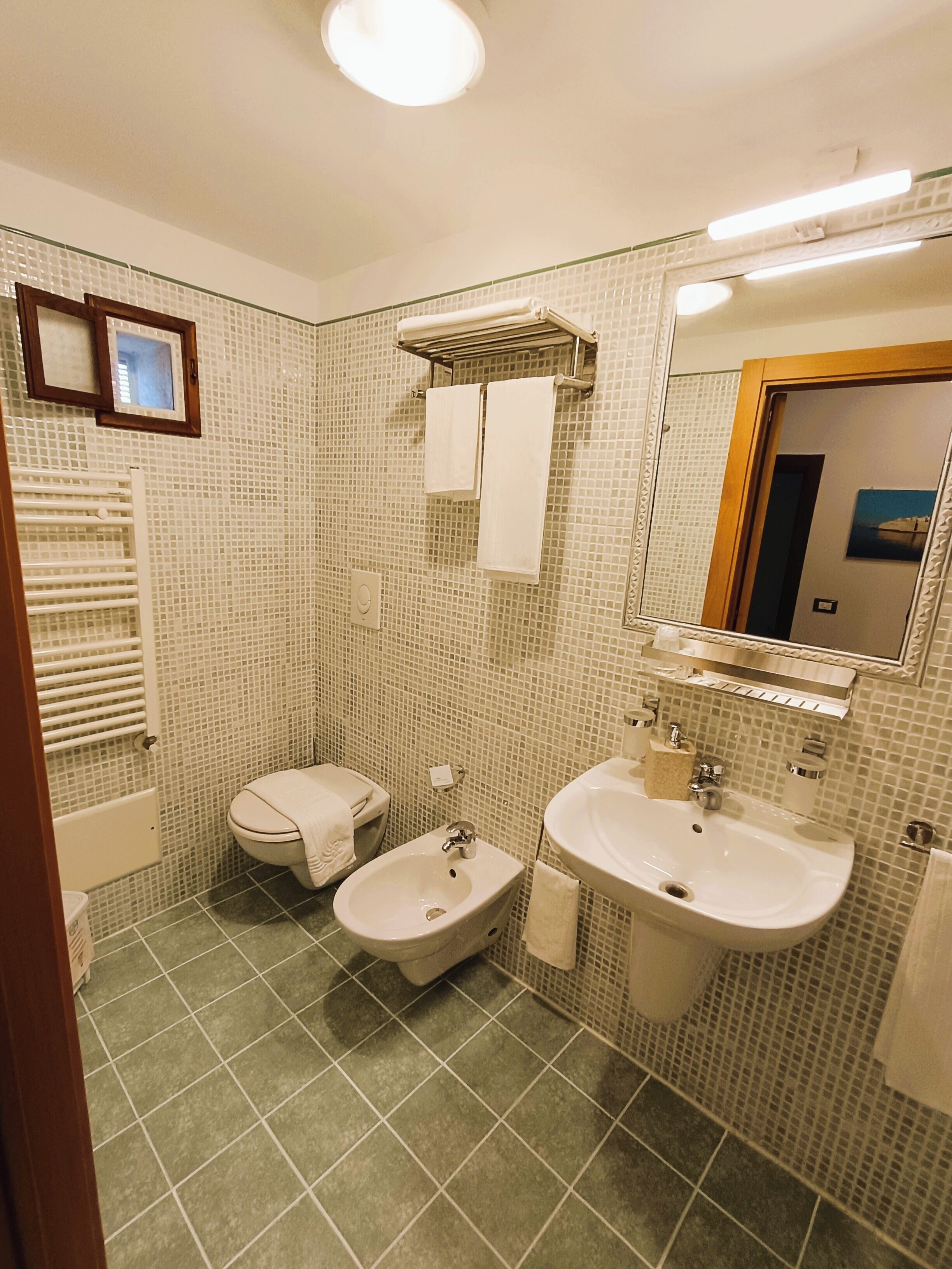 Ein Badezimmer mit Bidet, Toilette, Waschbecken und Spiegel.