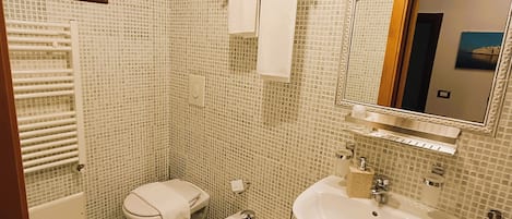 A bathroom with a bidet, a toilet, a sink, and a mirror.