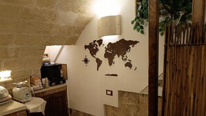 A kitchen with a world map on the wall, a coffee machine, and a rustic stone archway. - B&B Casa Cimino (Monopoli)