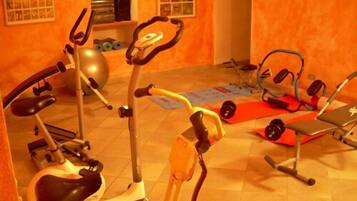 Una palestra in casa con attrezzature per allenamento, tra cui un ellittica, una cyclette e un tapis roulant.