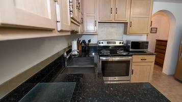 A kitchen with a stove, microwave, sink, and wooden cabinets.
