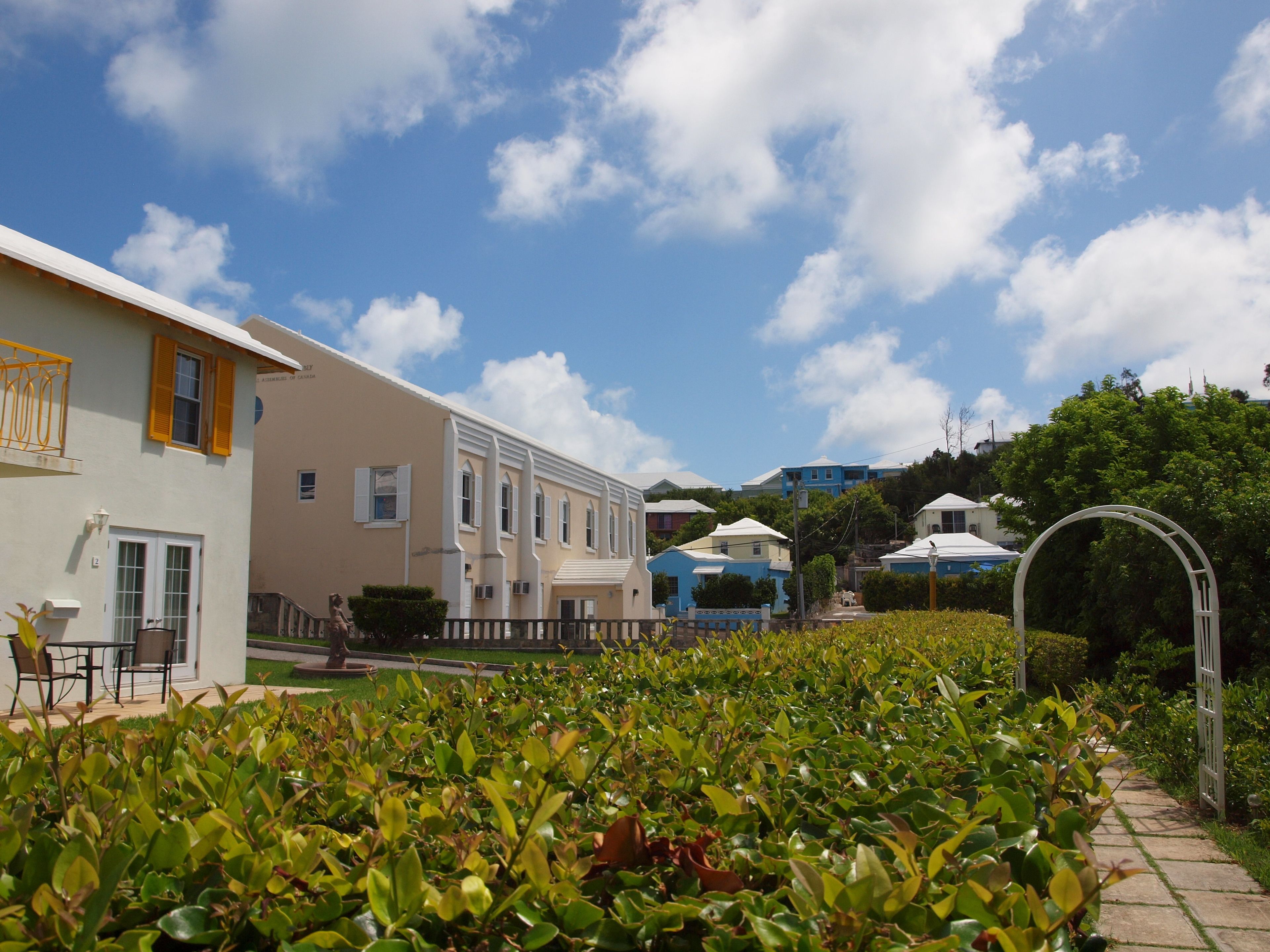 A row of residential buildings with a well-maintained garden in the foreground.