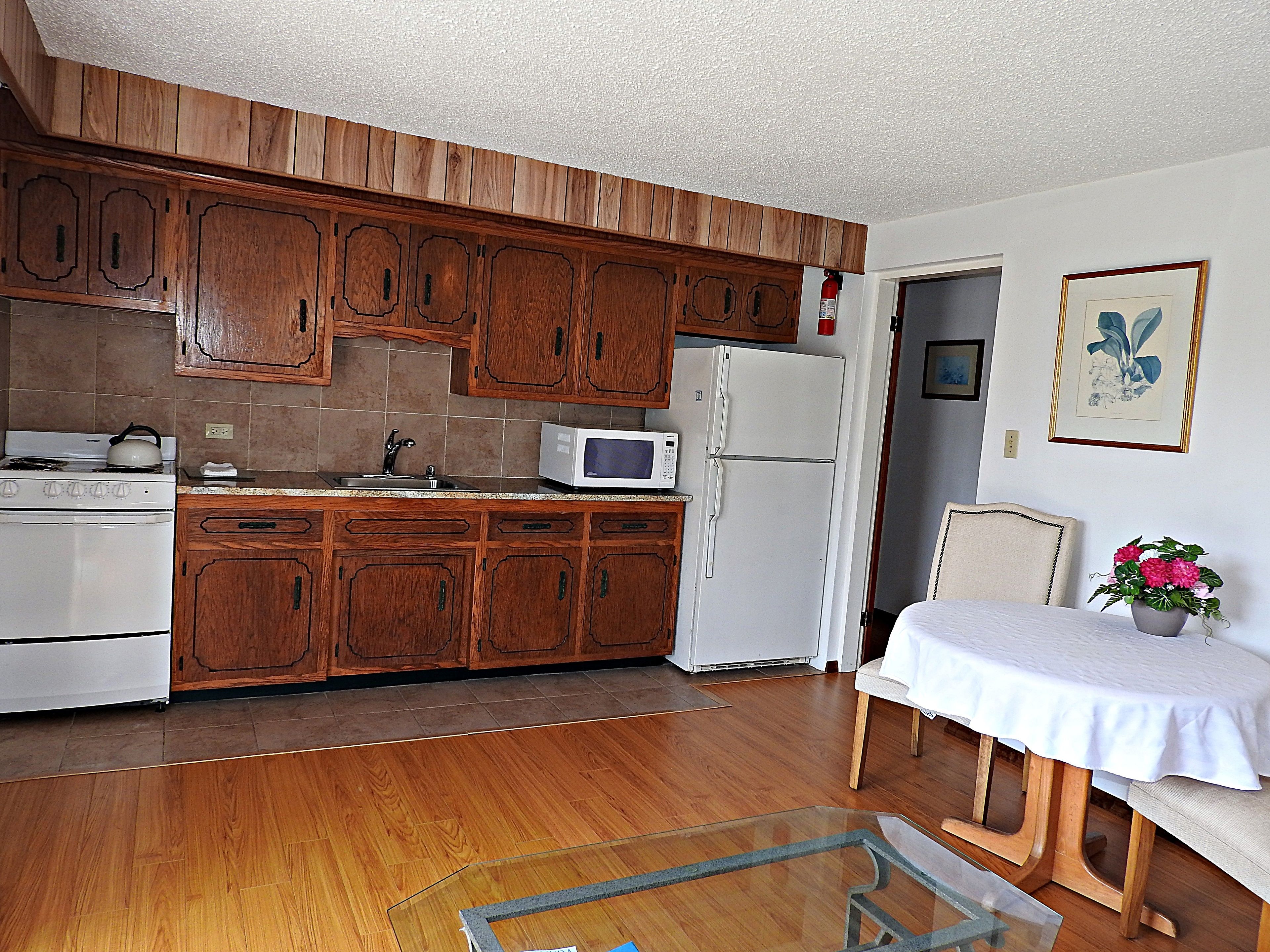 Una cocina con armarios de madera, estufa blanca, microondas y refrigerador.