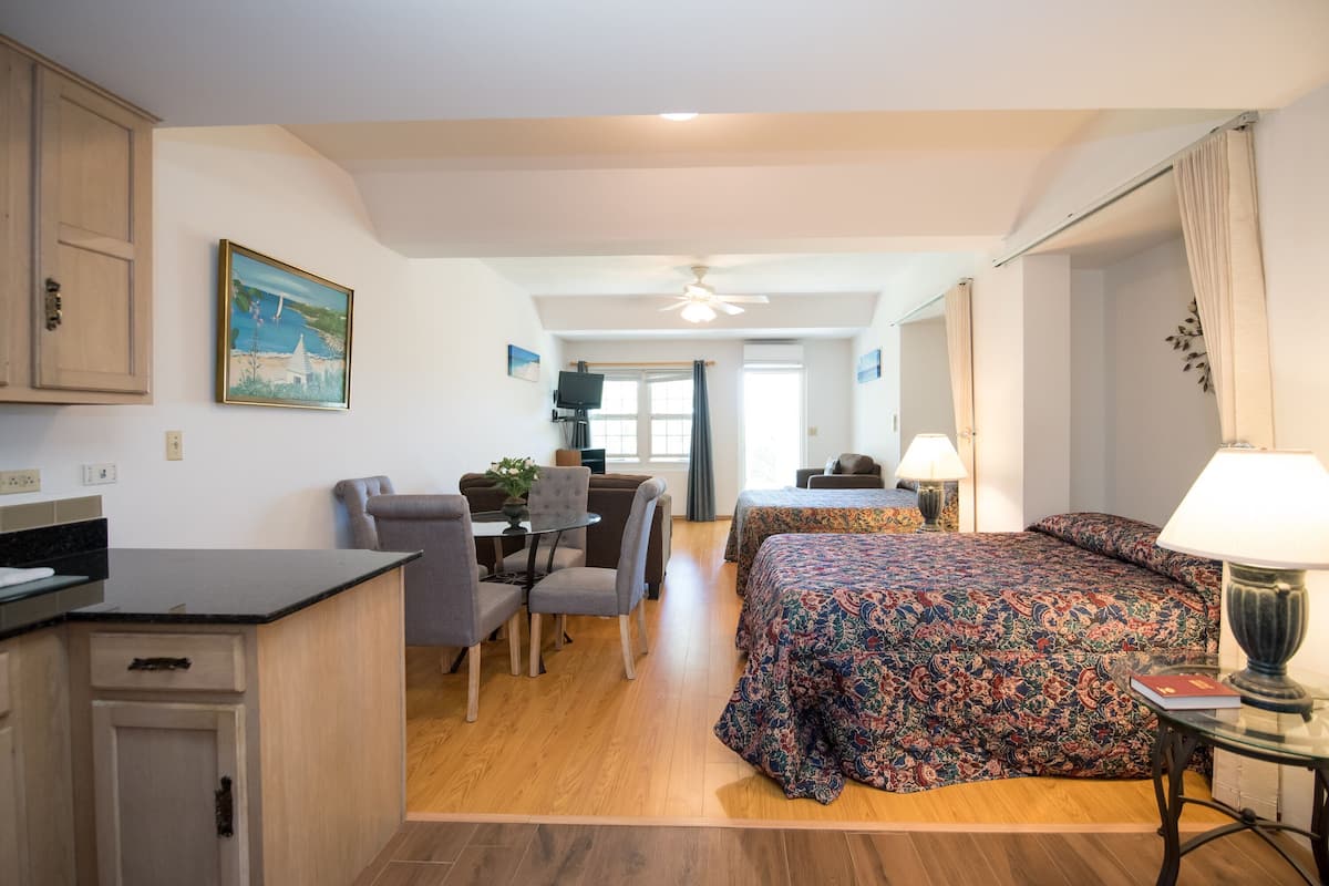 A hotel room with a bed, a desk, a chair, a table, and a TV.