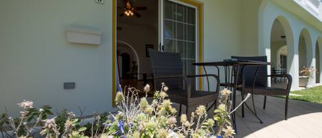 A covered patio with outdoor furniture, a sliding glass door, and a view of the interior.