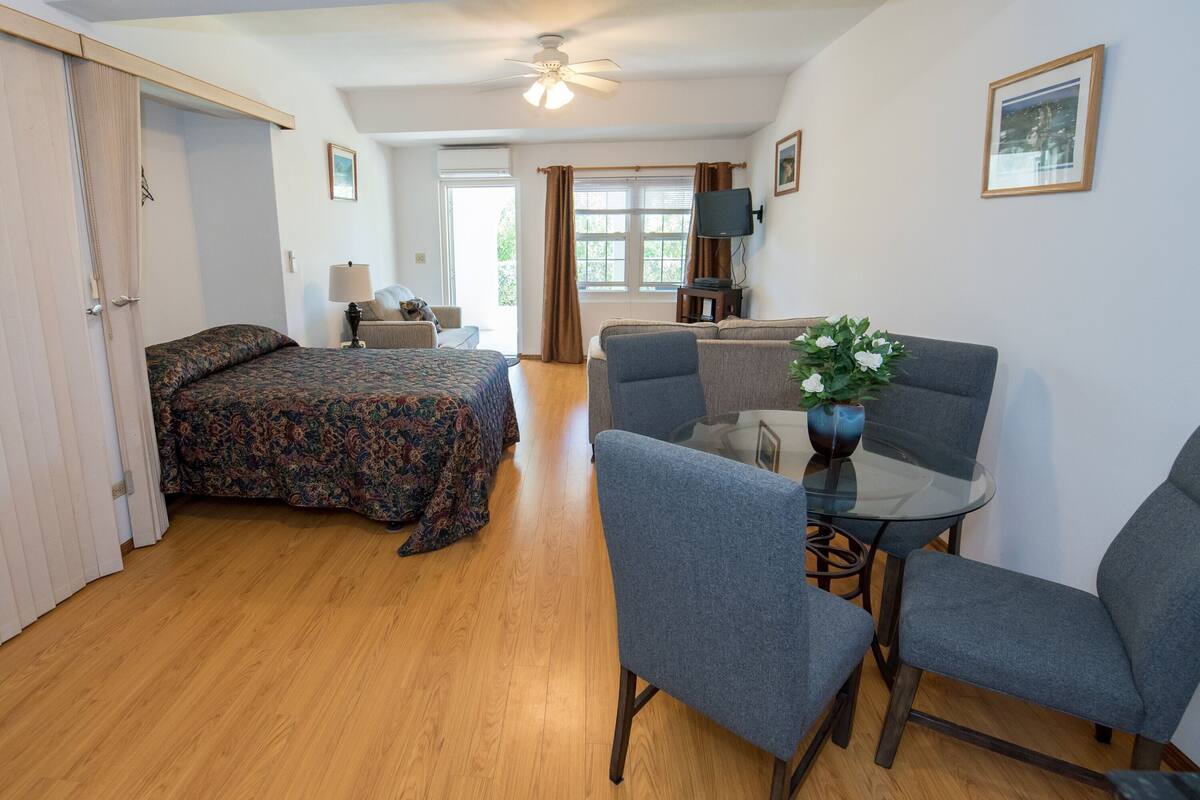 A hotel room with a bed, a sofa, a glass table, and a TV.