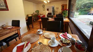 Un comedor con una mesa de madera dispuesta para una comida, sillas y vistas al exterior.