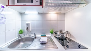 A modern kitchen with a microwave, a glass-top stove, a sink, and a dish soap dispenser.