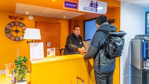 A reception desk with a clock, a sign reading "Welcome," and a sign for "Accueil."