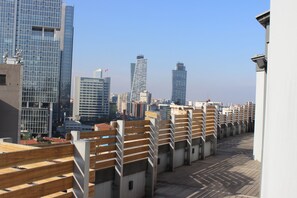 A rooftop terrace with wooden railings and a view of a city skyline with modern buildings. - The Leos Residence (Istanbul)
