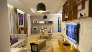 Una sala de estar moderna con sofá, mesa de centro, televisor y un comedor con sillas y mesa.