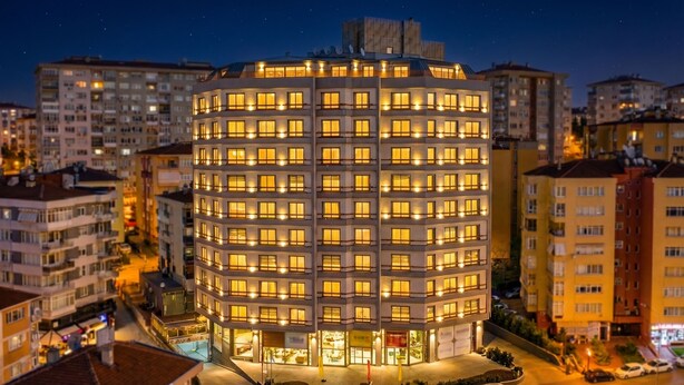 Un hotel de varios pisos con fachada circular, numerosas ventanas y una entrada central.