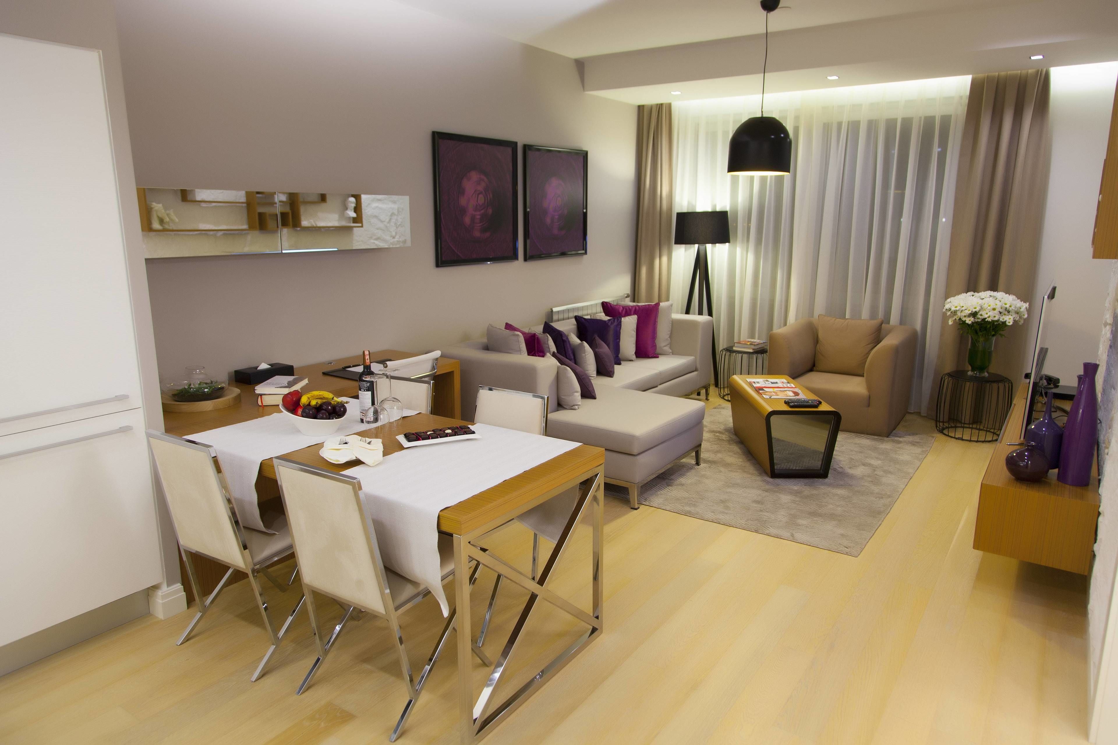 A modern living room with a sofa, coffee table, and dining area with chairs and a table.