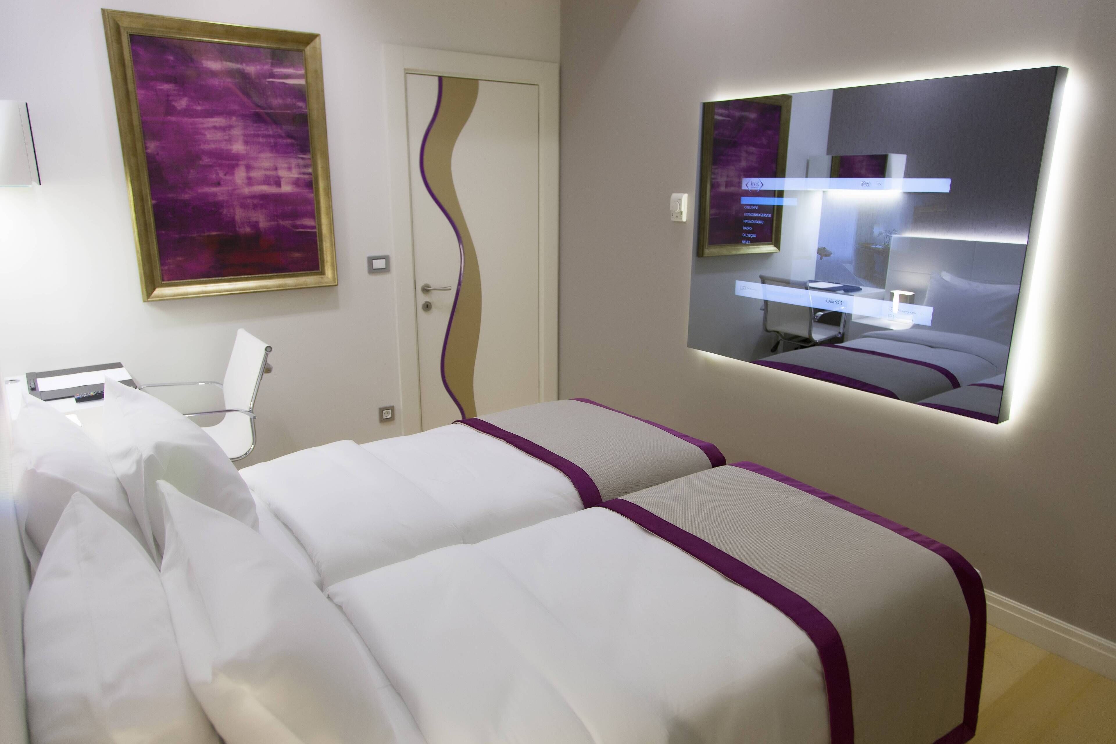 A hotel room with two beds, a large mirror, and a painting on the wall.
