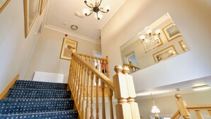 A staircase with wooden balusters and a blue carpeted landing. - Chestnuts House (Bath)