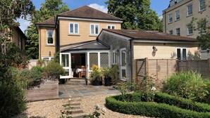 A two-story house with a patio and garden. - Chestnuts House (Bath)