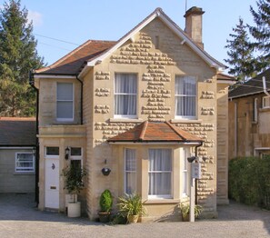A two-story house with stone facade and a tiled roof.