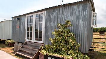 Een klein, laag gebouwd metalen gebouw met een veranda en een bordje met de tekst 'REG'.