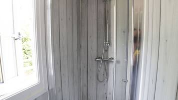 Ein Duschbereich mit Glastür, Holzwänden und einem Fenster.