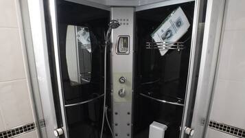 Um chuveiro de entrada livre com painel de controle, secador de mãos e porta-toalhas.