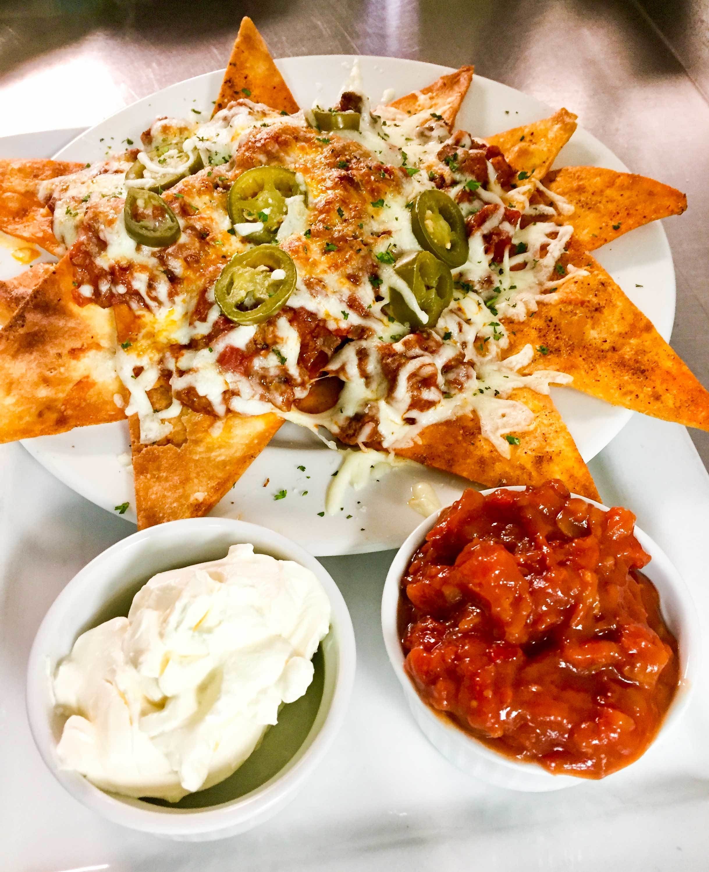 Nachos topped with cheese, jalapeños, and a side of sour cream and salsa.