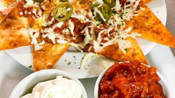 Nachos topped with cheese, jalapeños, and a side of sour cream and salsa.