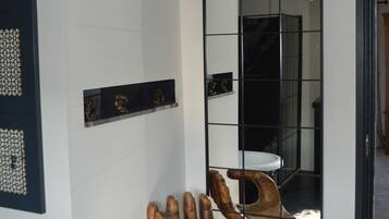 Bagno con una scultura a forma di mano in legno, un lavandino bianco e un ampio specchio che riflette l'ambiente.