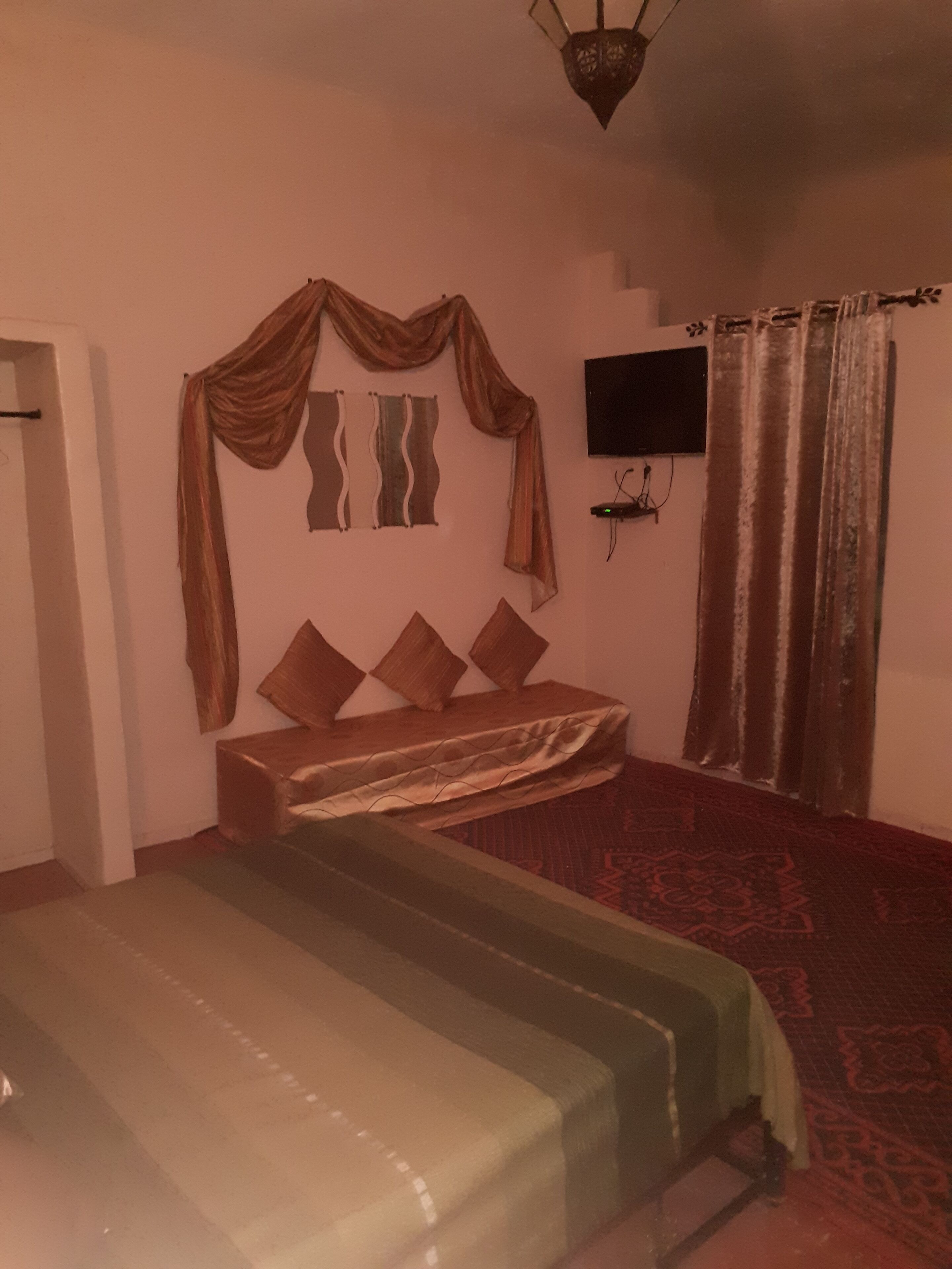 A bedroom with a bed, a TV mounted on the wall, and a curtain.