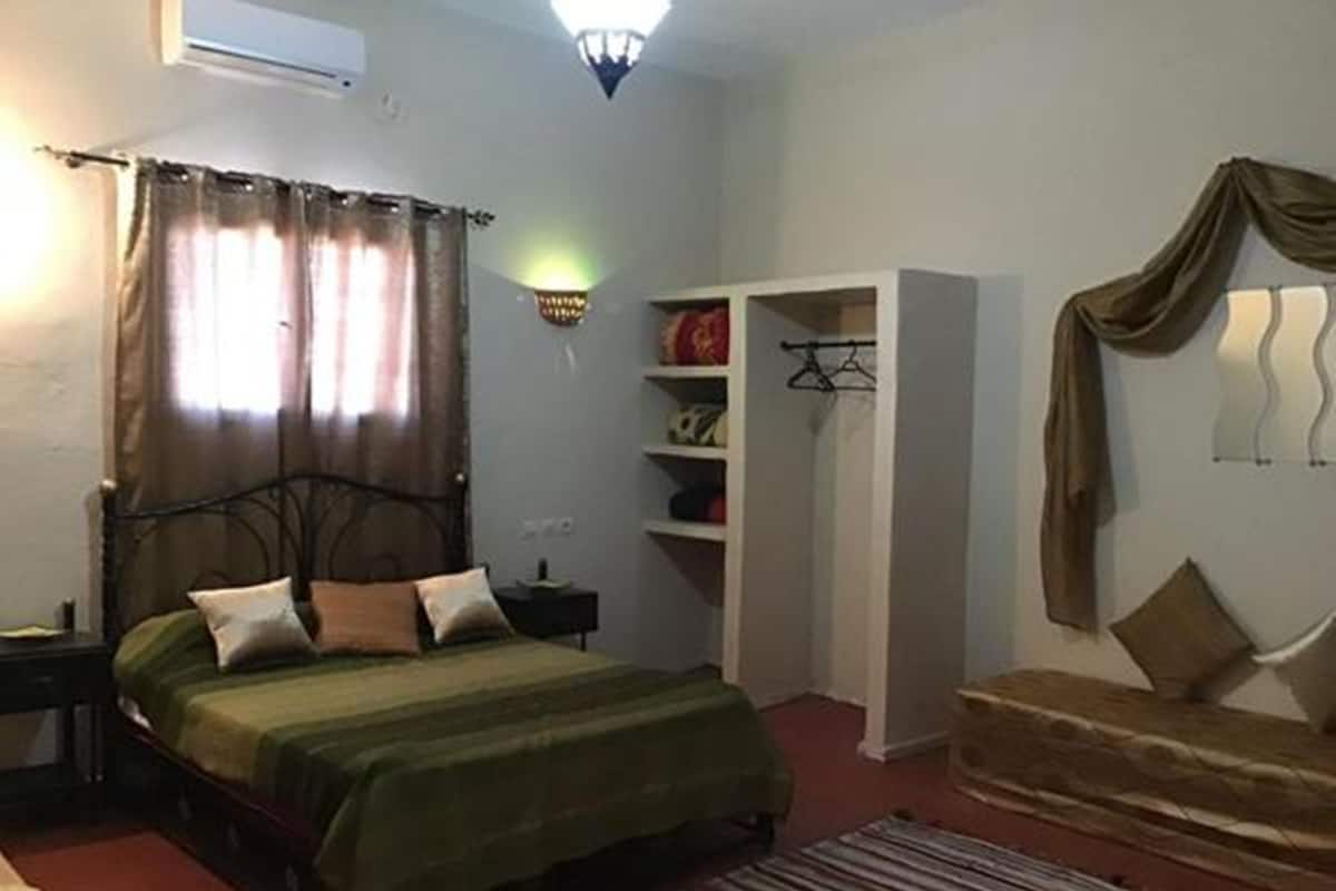 A bedroom with a bed, a wardrobe, a nightstand, and a lamp.