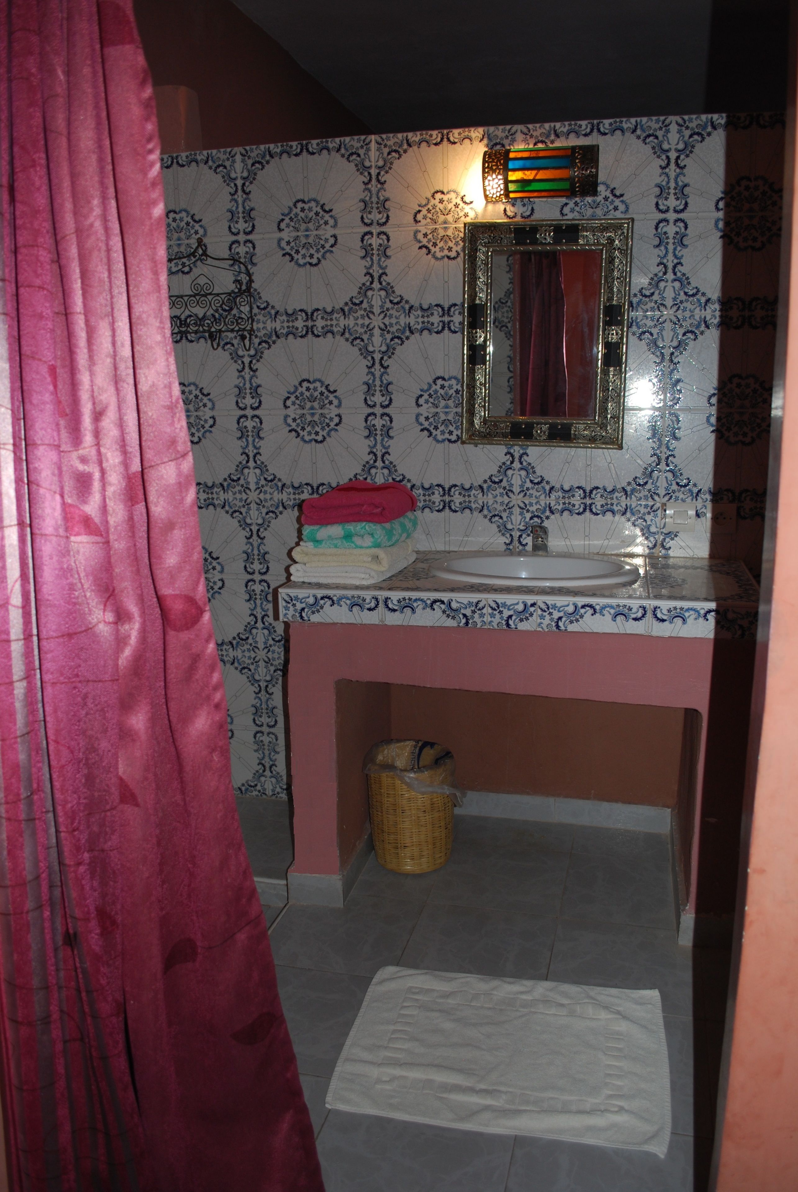 Un baño con lavamanos, espejo y azulejos estampados.
