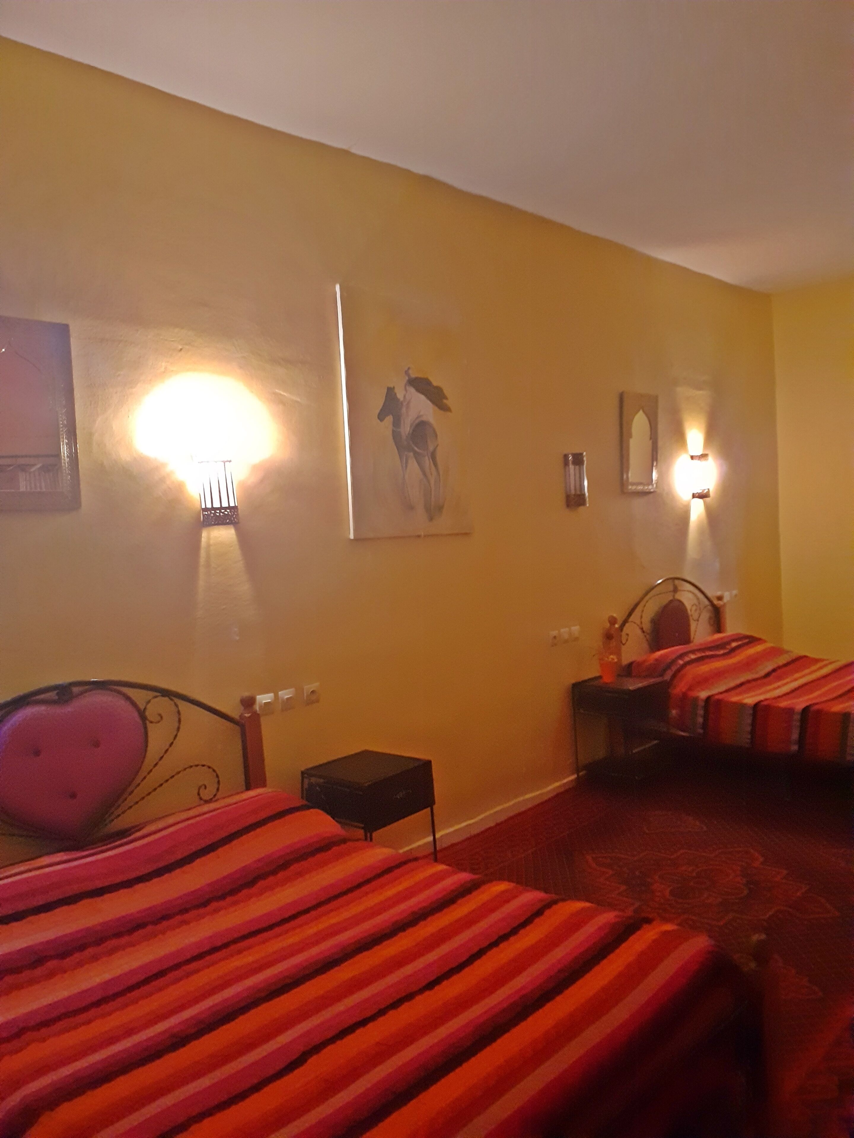Una habitación de hotel con dos camas, una mesita pequeña y luces fijadas a la pared.