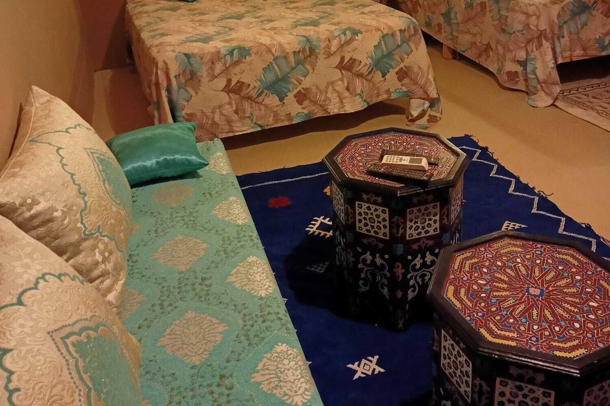 A hotel room with two beds, a sofa, and a decorative coffee table.